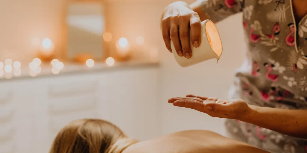 Óleo de massagem sendo despejado na mão antes de uma sessão de massagem sensual